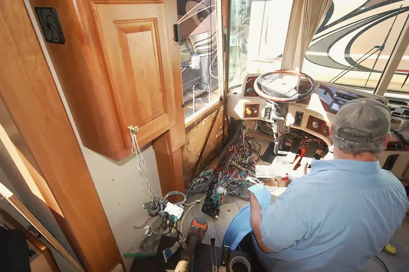 Technician inspecting the wiring behind a motorhome dashboard